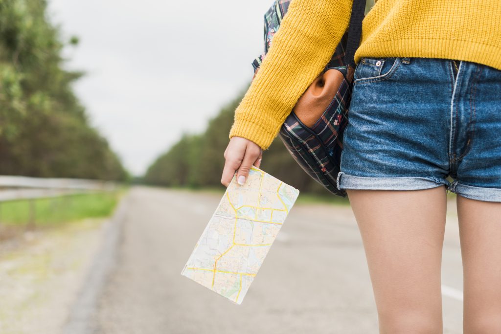 femme sur une route qui cherche sa voie et qui tient une carte routière pour avancer